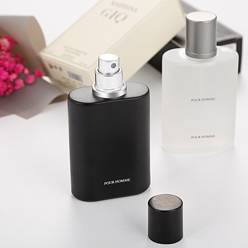 Two perfume bottles labeled 'Pour Homme' on a white surface with a blurred background.